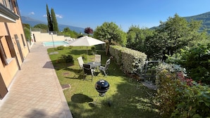 A patio with a barbecue grill, outdoor seating, and a swimming pool.