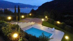 A swimming pool with a view of a lake and mountains at dusk.