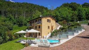 A two-story building with a swimming pool, outdoor seating, and a staircase leading to the upper floor.