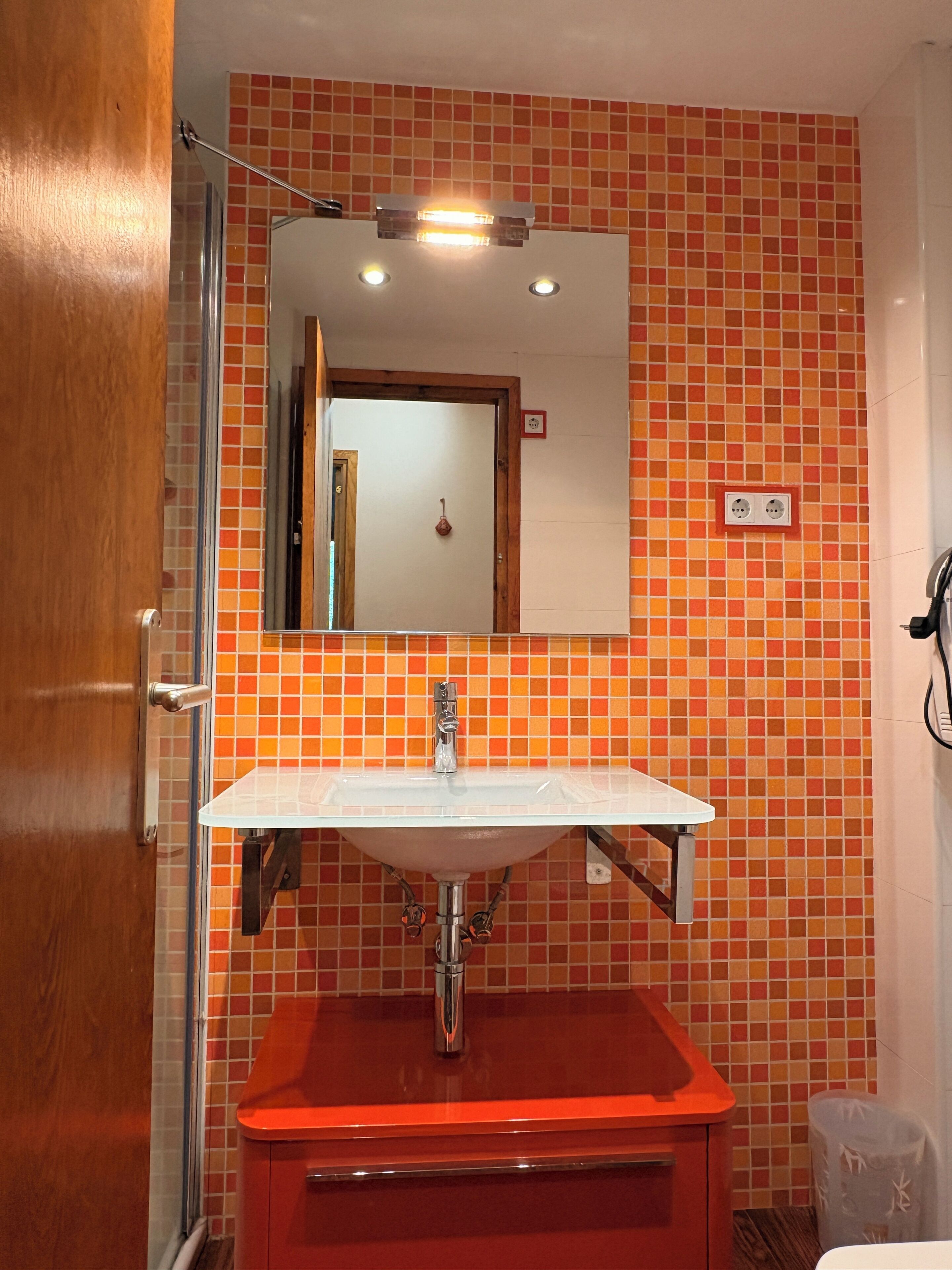 Une salle de bain avec un mur carrelé, un lavabo, un miroir et une porte.