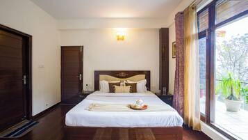 Une chambre d’hôtel avec un grand lit, une table de chevet, une lampe fixée au mur et une fenêtre avec des rideaux.