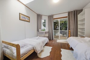 Ein Schlafzimmer mit zwei Betten, einem Fenster, einem Balkon und einem kleinen Schreibtisch.