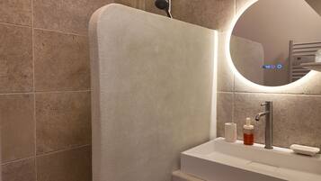 Un baño moderno con ducha, lavamanos y espejo.