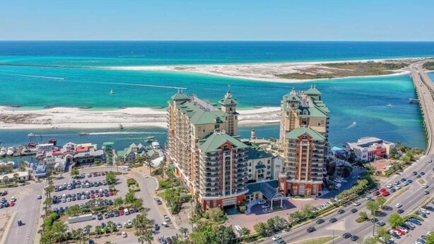 A coastal hotel with multiple buildings, a parking lot, and a view of the ocean and beach. - Breathtaking Views Emerald Grande 3BR/2BA 904E (Destin)