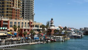 A waterfront hotel with multiple balconies, a lighthouse, and boats docked. - Breathtaking Views Emerald Grande 3BR/2BA 904E (Destin)