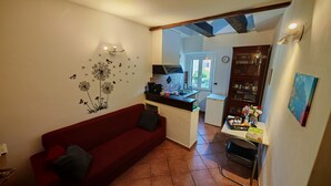 Een knus woongedeelte met een rode bank, een kitchenette, een eethoek en uitzicht op de omgeving.