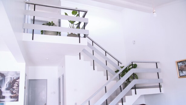 Una escalera moderna con barandas blancas y plantas en macetas, que conduce a un piso superior.