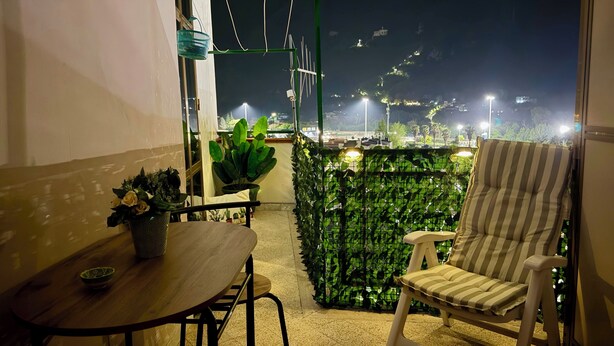 A balcony with a table, chairs, potted plants, and a view of a cityscape at night. - Susanna's House, a carefree stay a stone's throw from downtown (Nocera Inferiore)