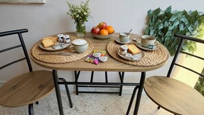 A round wooden table with a woven placemat, two chairs, a bowl of fruit, a vase with flowers, and a potted plant. - Susanna's House, a carefree stay a stone's throw from downtown (Nocera Inferiore)