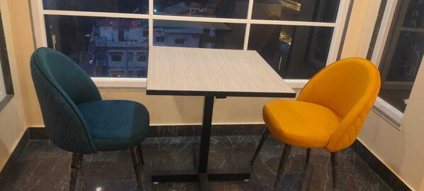 A corner room with a window, a small table, two chairs, and a marble floor. - Starry Hills Resort (Kanda)