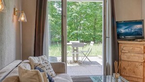 Une pièce comprenant un canapé, un téléviseur, un meuble en bois et une table en verre.