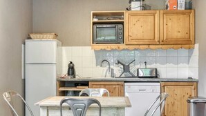 Une cuisine équipée d’un réfrigérateur, d’un four à micro-ondes, d’un grille-pain, de meubles en bois et d’un crédence carrelée.