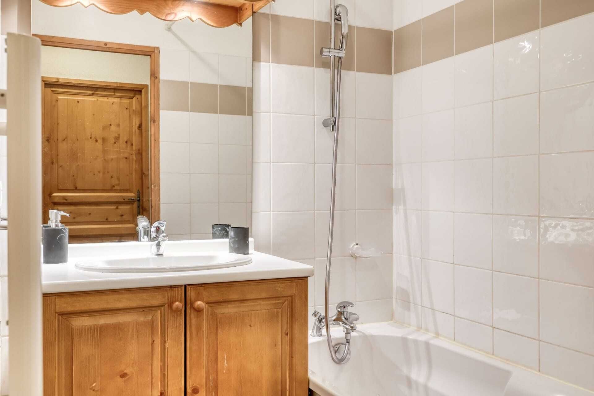 Une salle de bain avec un meuble-lavabo en bois, un évier, un miroir et une douche.