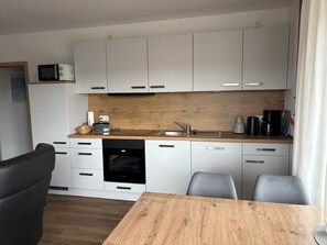 Eine moderne Küche mit weißen Schränken, einer Holz Arbeitsplatte, einem eingebauten Backofen und einem Essbereich mit Tisch und Stühlen.
