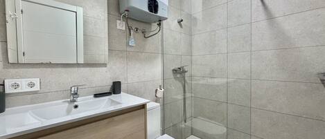 Un baño moderno con lavamanos doble, inodoro, ducha con cabina de vidrio y calefacción integrada.
