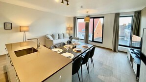 Een moderne hotelkamer met een zithoek, een bank en een groot raam met uitzicht op de stad.