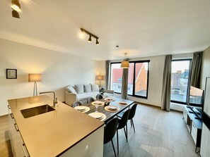 Ein modernes Hotelzimmer mit Essbereich, einer Sitzecke und einem großen Fenster mit Blick auf die Stadt.