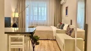 Ein modernes Hotelzimmer mit Bett, Schreibtisch, Stuhl und einem großen Fenster mit Vorhängen.