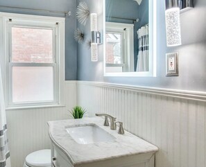 A bathroom with a white vanity, a window, a mirror, and decorative wall sconces. - 3-bedroom house in charming St Matthews Walking distance to multiple restaurants (Saint Matthews)