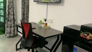 Een moderne kantoorruimte met een bureau, stoel, televisie en een kleine koelkast.