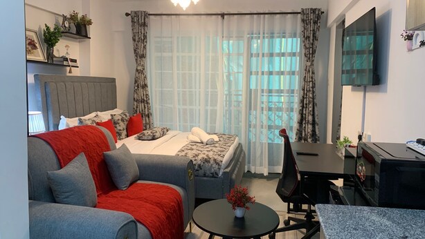 Een moderne hotelkamer met een bed, een slaapbank, een bureau en een televisie.