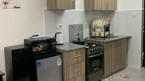 Een kleine keuken met houten kastjes, een koelkast, een fornuis en een magnetron.