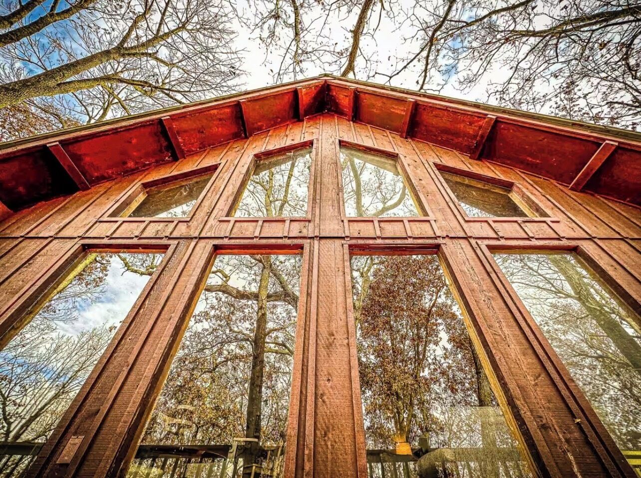 Une structure en bois dotée de grandes fenêtres et d’un toit rouge.