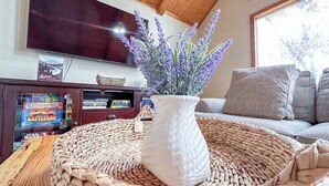 A living room with a television, a woven basket, and a vase with lavender. - Eremos – A Peaceful Browside Escape with Unforgettable Views (Mentone)