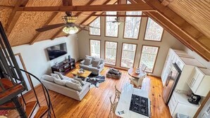 A spacious loft with a high ceiling, large windows, a cozy seating area, and a kitchen. - Eremos – A Peaceful Browside Escape with Unforgettable Views (Mentone)
