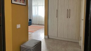 A hallway with a patterned ottoman, a wardrobe, and a painting on the wall. - BSKYLINE bright 2-rooms apartment at vibrant area (Almaty)