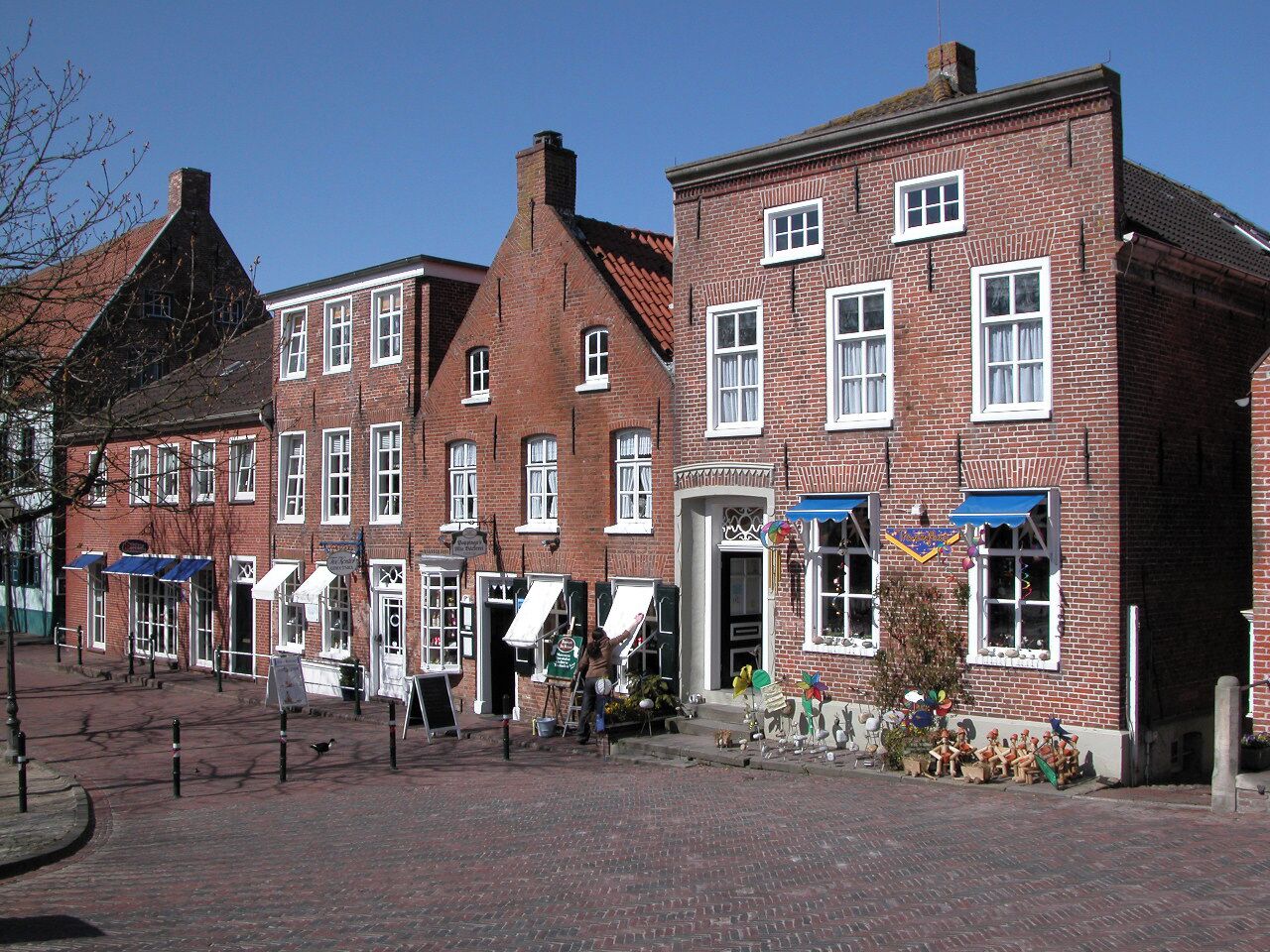 Eine typische europäische Straße mit roten Backsteingebäuden, Kopfsteinpflaster und blauem Himmel.