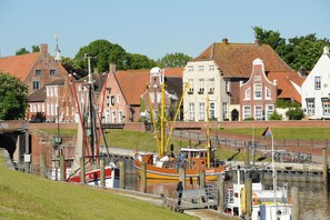 A canal with a boat docked, buildings with traditional architecture, and a clear sky. - Apartment Maike 2, renovated, central, yet quiet location with balcony (Krummhörn)