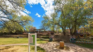 A park with a paved walkway, a signpost, and colorful murals on the walls. - Skylight Loft (Santa Fe)