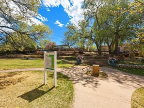 A park with a paved walkway, a signpost, and colorful murals on the walls. - Skylight Loft (Santa Fe)