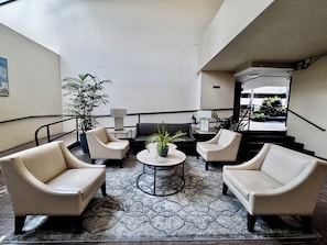 A lobby with two sofas, a coffee table, and a potted plant.