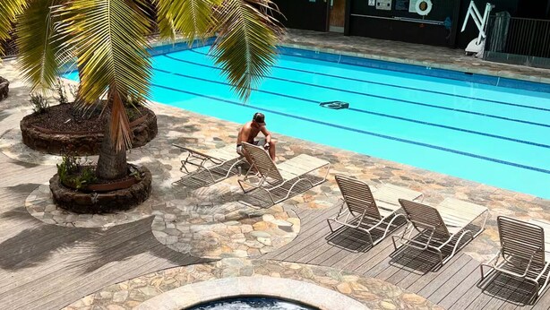 Ein Pool mit Liegestühlen, einem Whirlpool und einer Palme.