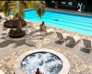 A swimming pool with lounge chairs, a hot tub, and a palm tree. - PenthouseCloseTo HPU&CruiseHugeTerrace withParkingOne and half Bath up  16person (Honolulu)