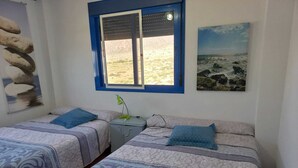 Quarto com duas camas, uma janela, um abajur e um quadro.