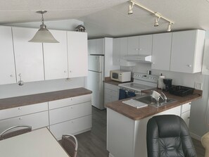A modern kitchen with white cabinetry, a built-in microwave, a stove, and a sink. - Cozy 2-bedroom home in beautiful Palmetto with spectacular waterfront views. (Palmetto)
