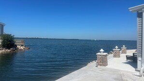 A waterfront property with a dock, stone pillars, and a clear view of the water. - Cozy 2-bedroom home in beautiful Palmetto with spectacular waterfront views. (Palmetto)