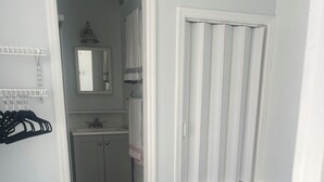 A bedroom with a bed, a bathroom with a sink and mirror, and a door leading to another room. - Cozy 2-bedroom home in beautiful Palmetto with spectacular waterfront views. (Palmetto)