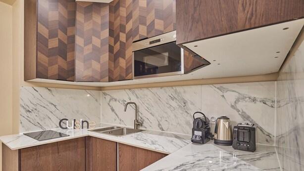 Una cocina con encimera de mármol, armarios de madera, horno empotrado y cafetera.