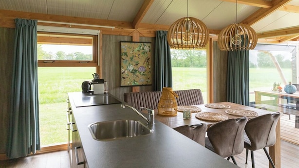 A kitchen with a large island, a dining area with a table and chairs, and a view of the outdoors.