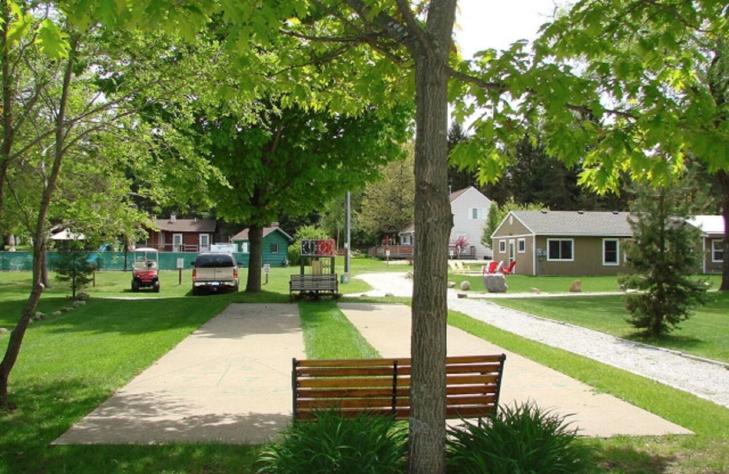 A park with a paved walkway, benches, and a playground area.