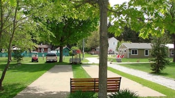 A park with a paved walkway, benches, and a playground area.