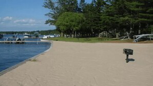 Une plage de sable avec une boîte aux lettres et un quai où sont amarrés des bateaux.