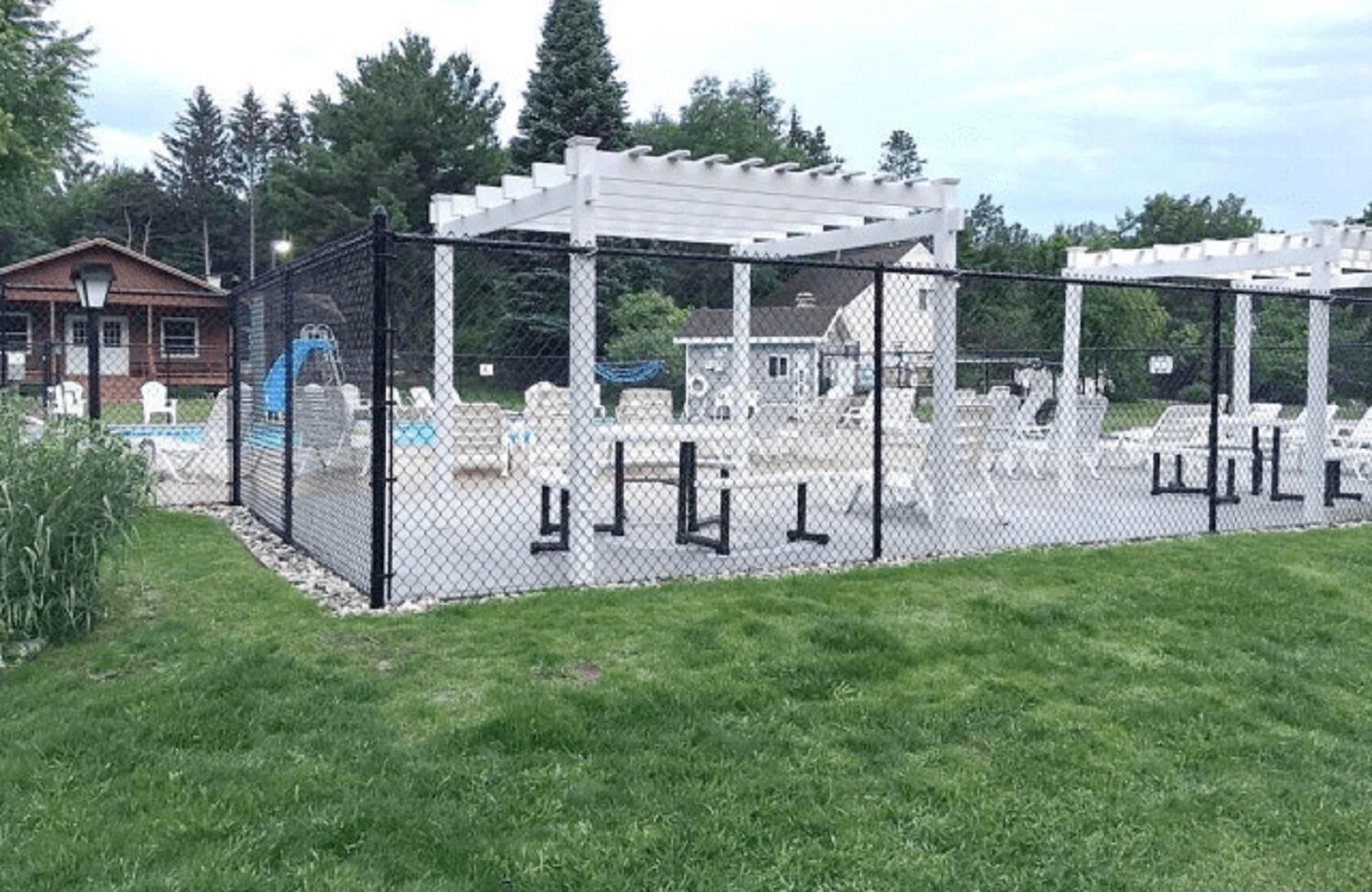 A fenced outdoor area with a pergola, seating, and a pool.