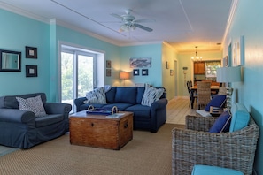 A living room with a sofa, a coffee table, and a wicker chair.