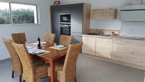 Cozinha moderna com uma mesa de jantar posta para seis pessoas, rodeada por cadeiras de vime.