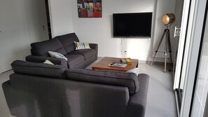 A modern living room with a grey sofa, a coffee table, and a flat-screen TV mounted on the wall. - Vacation home 6 people 3 bedrooms Loctudy (Loctudy)